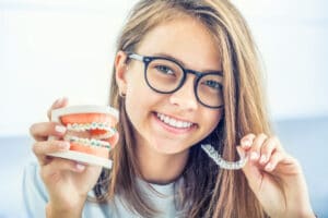 teenager holding teen invisalign and braces